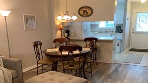 Un espace repas comprenant une table ronde et des chaises, un pouf capitonné et un luminaire suspendu.