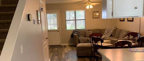 A spacious living room with a sofa, chairs, and a kitchen area with cabinets.