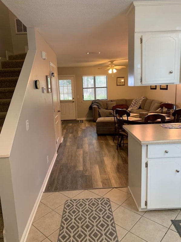 A spacious living room with a sofa, chairs, and a kitchen area with cabinets.