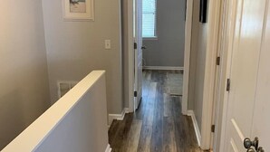 Un couloir étroit avec un plancher en bois et des murs blancs.