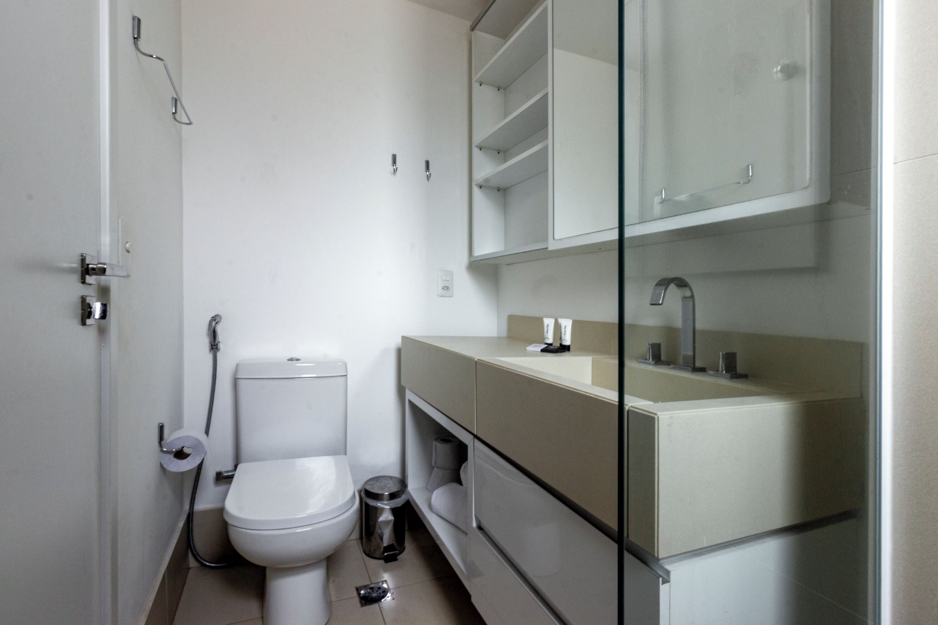Un baño moderno con inodoro, lavamanos y cabina de ducha de vidrio.