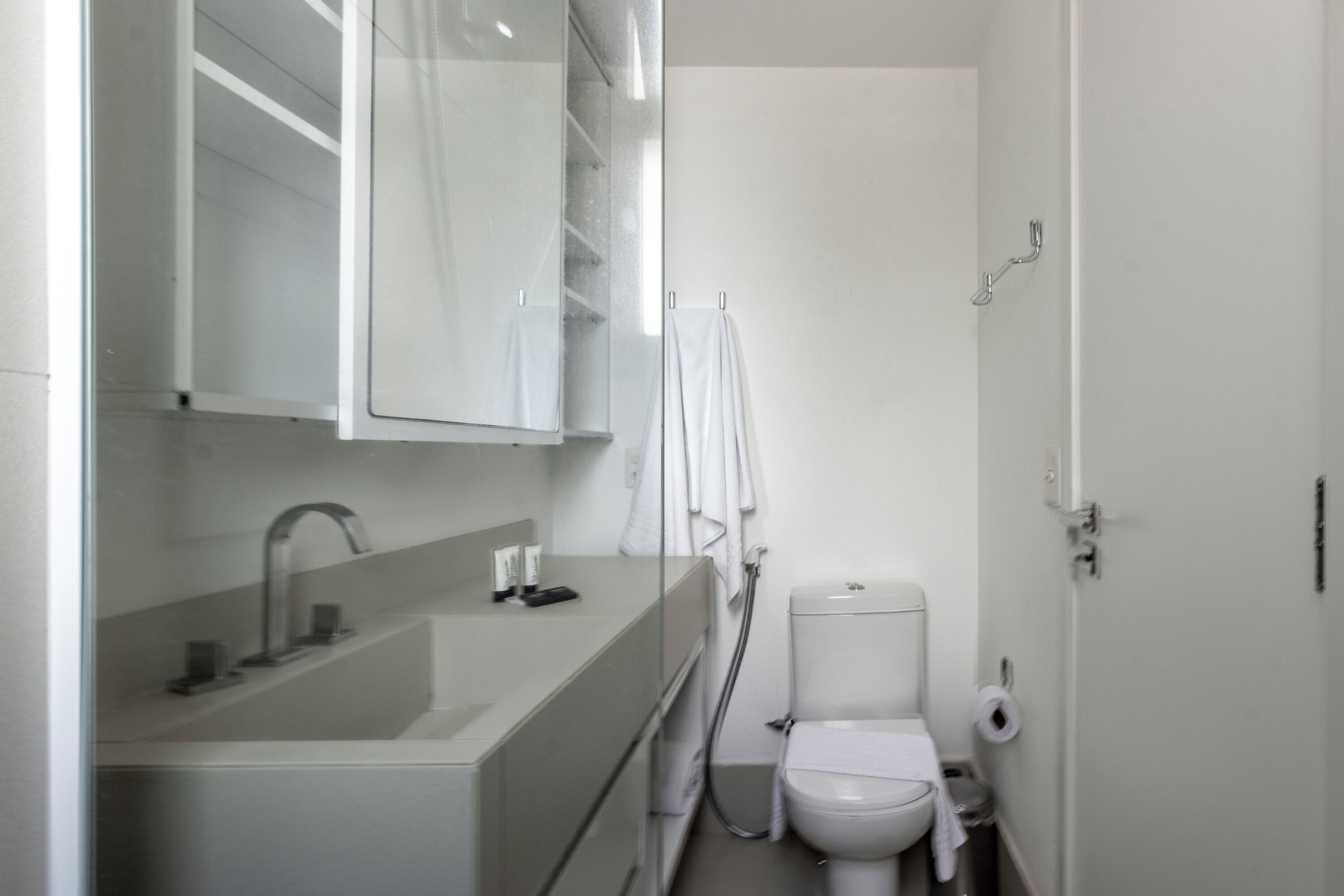 A modern bathroom with a sink, mirror, toilet, and towel rack.