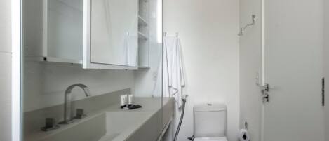 A modern bathroom with a sink, mirror, toilet, and towel rack.