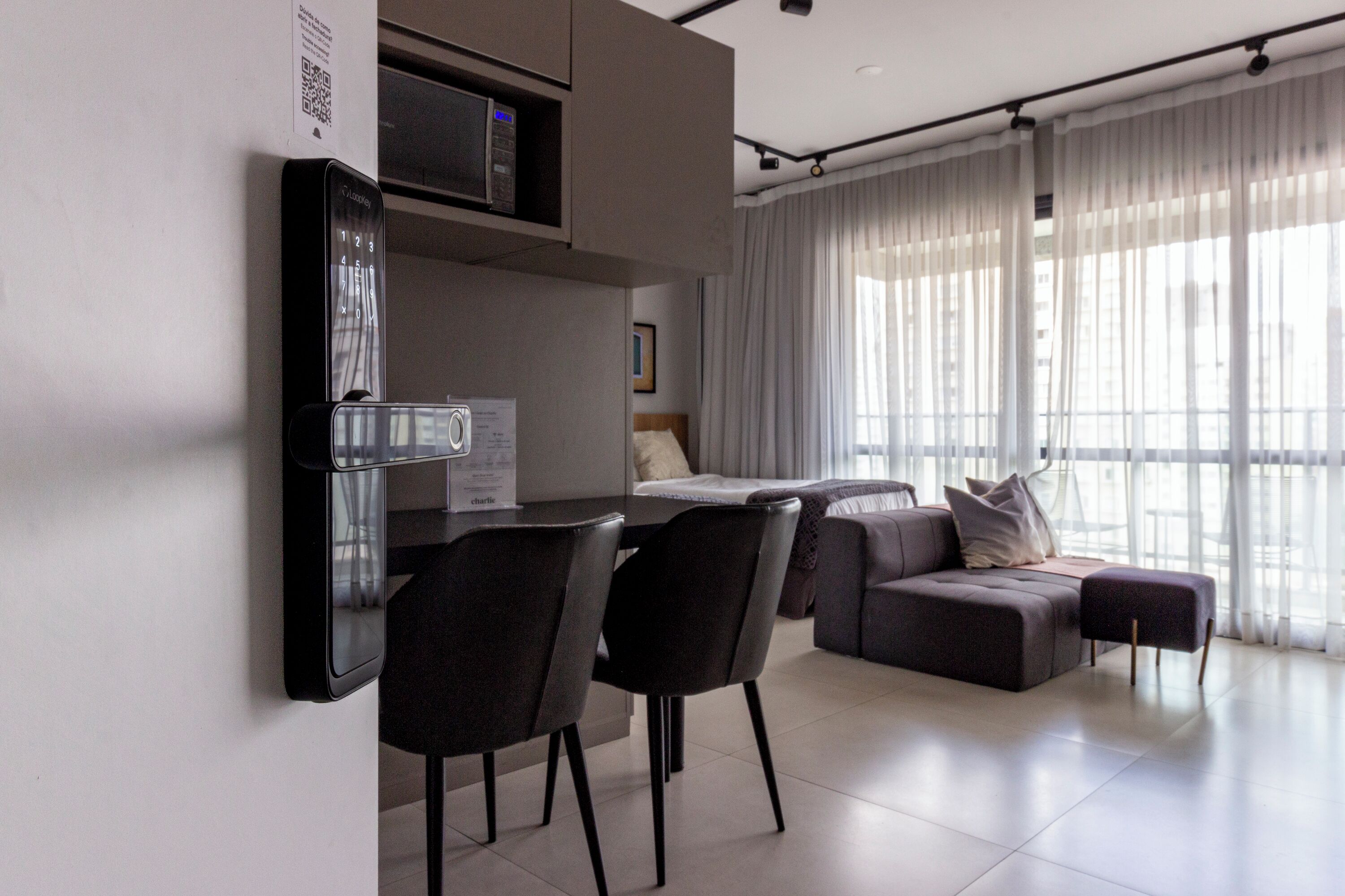 Una sala moderna con un sofá, sillas, una mesa de comedor y una zona de cocina con un microondas.