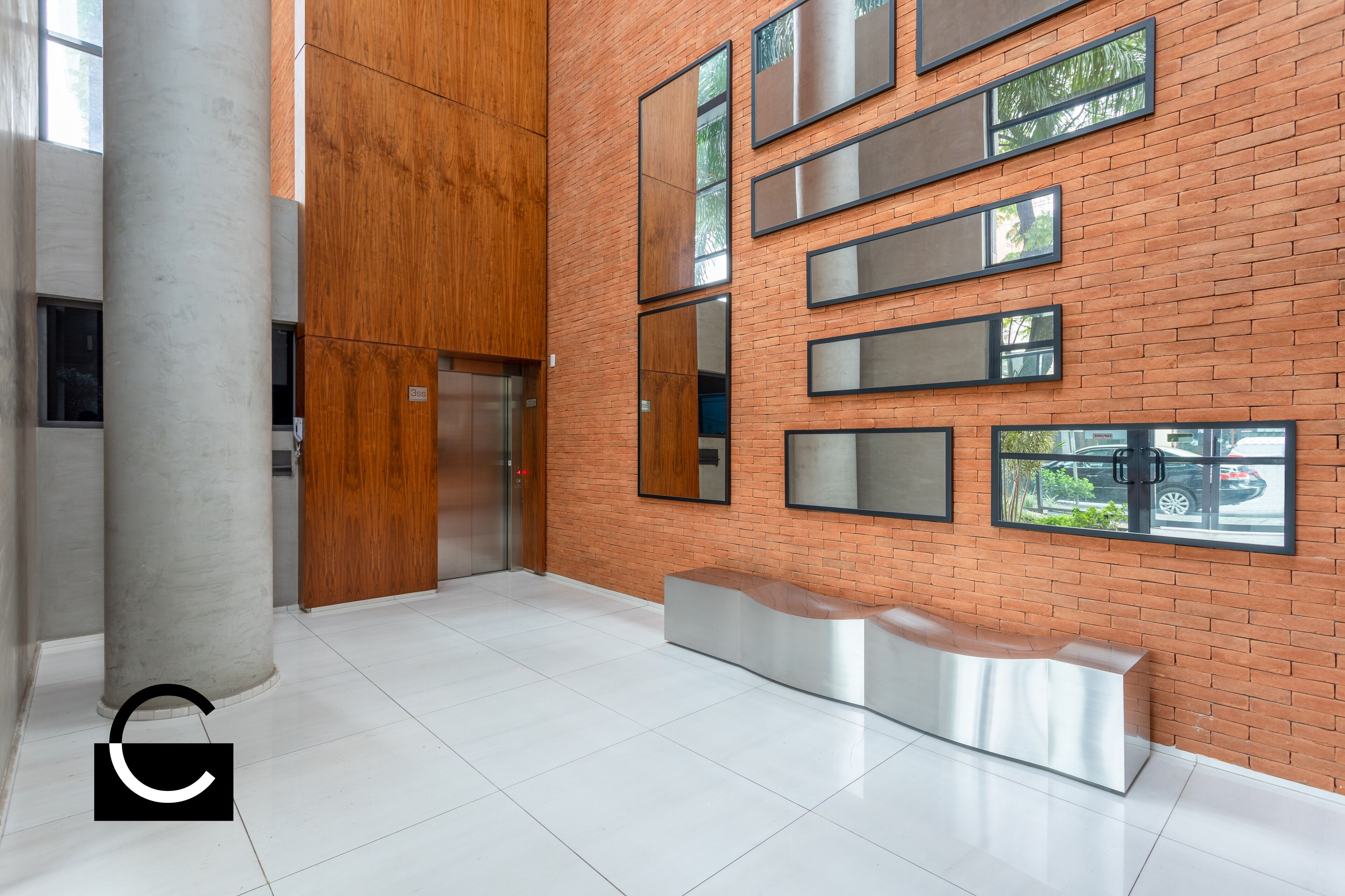 Um hall moderno com parede de tijolos, espelhos grandes e balcão de recepção.
