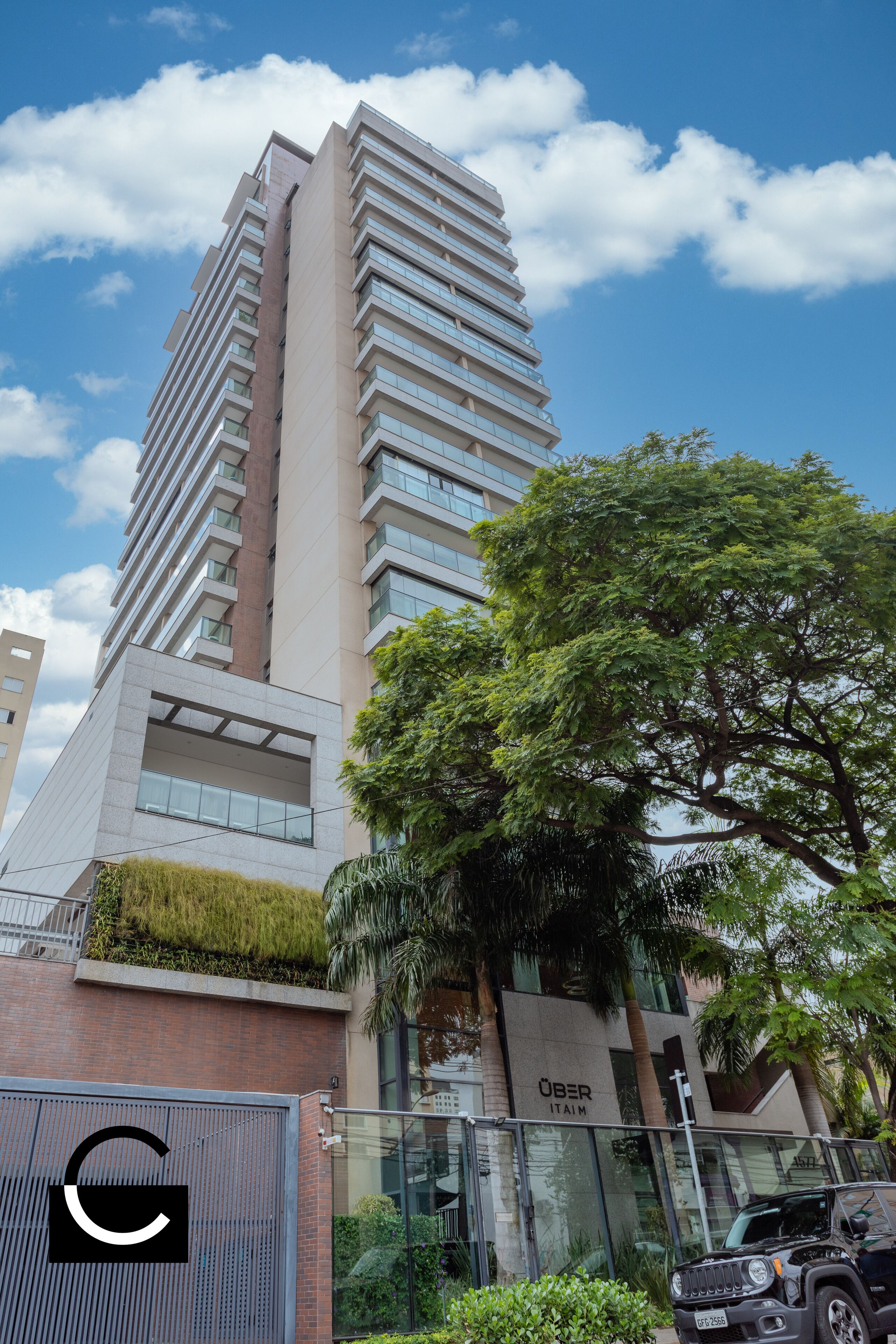A tall, modern building with a glass facade and a sign that reads "UBER ITAIM".
