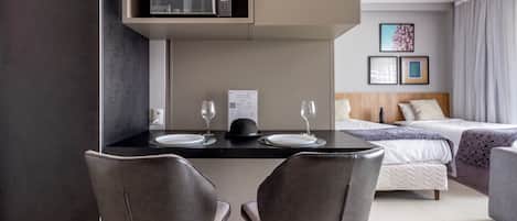 Una habitación de hotel moderna con comedor, cama y vistas a la ciudad.