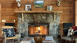L’intérieur d’un chalet confortable, avec une cheminée en pierre, des meubles en bois et un tapis rustique.