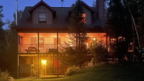 Une maison en bois à deux étages, dotée d’un balcon et d’un chien dans le jardin.