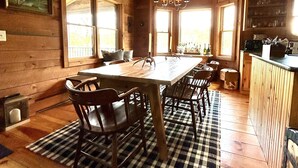L’intérieur d’un chalet en bois comprend un coin repas, de grandes fenêtres et une cuisine.