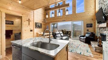A cozy cabin interior with a kitchen, dining area, and a fireplace.