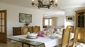 A dining area with a glass table, wooden chairs, a chandelier, and a cabinet. - Villa Llobets I (Llucmajor)