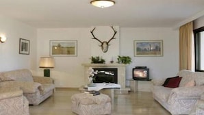 A living room with two sofas, a fireplace, and a mounted deer head. - Villa Llobets I (Llucmajor)