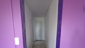 A narrow hallway with purple walls and a tiled floor leading to a door at the end. - Apartement F3 en bas de Villa (Basse-Pointe)