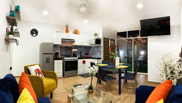 Une cuisine moderne équipée d’un réfrigérateur, d’une cuisinière et d’un four à micro-ondes. Un coin repas avec une table et des chaises est également disponible.
