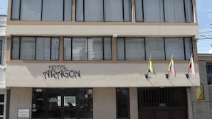 A hotel named "Hotel Dragon" with a modern facade, large windows, and multiple flags displayed outside.