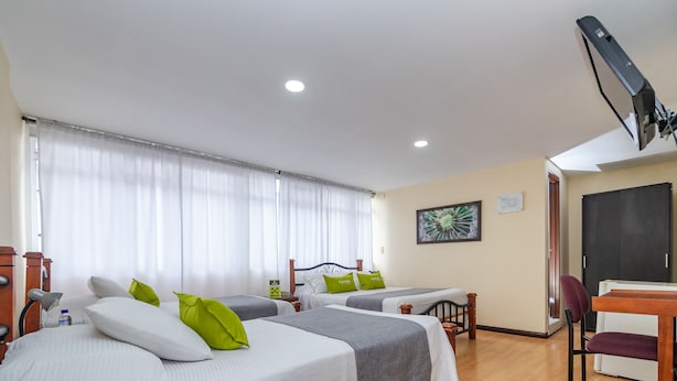 A hotel room with three beds, a desk, and a chair.