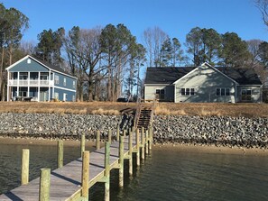 A wooden pier extending into a body of water with a rocky shoreline.