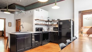 Eine moderne Küche mit schwarzen Geräten, Holzboden und einem Essbereich mit Holztisch und Stühlen.