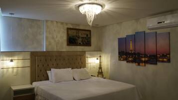 A hotel room with a large bed, a chandelier, a painting of the Eiffel Tower, and a cityscape view.