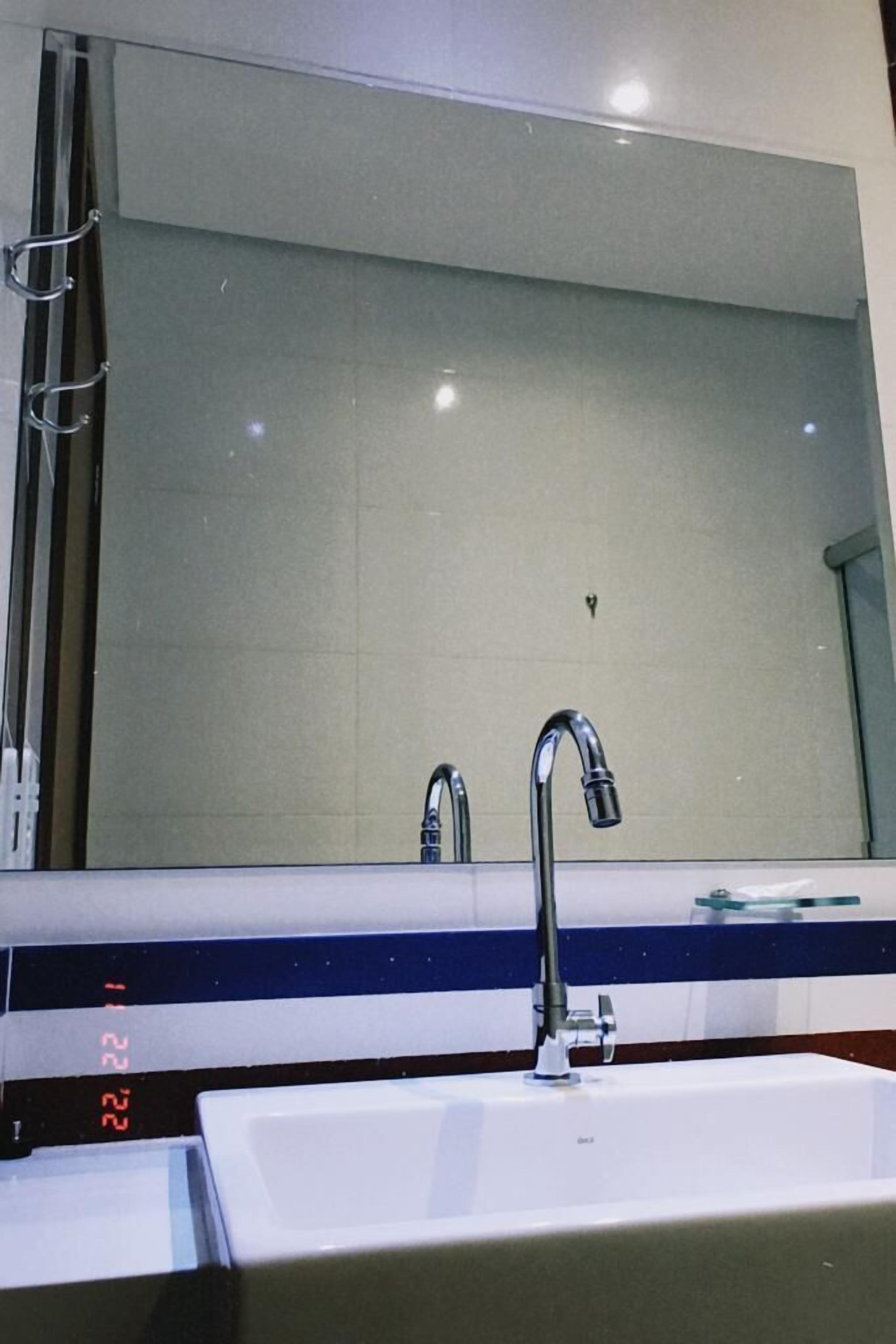 A bathroom with a large mirror, a white sink, and a modern faucet.