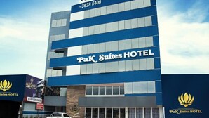 Un edificio de hotel de varios pisos con un cartel que dice 'PaK Suites HOTEL' y un número de contacto.