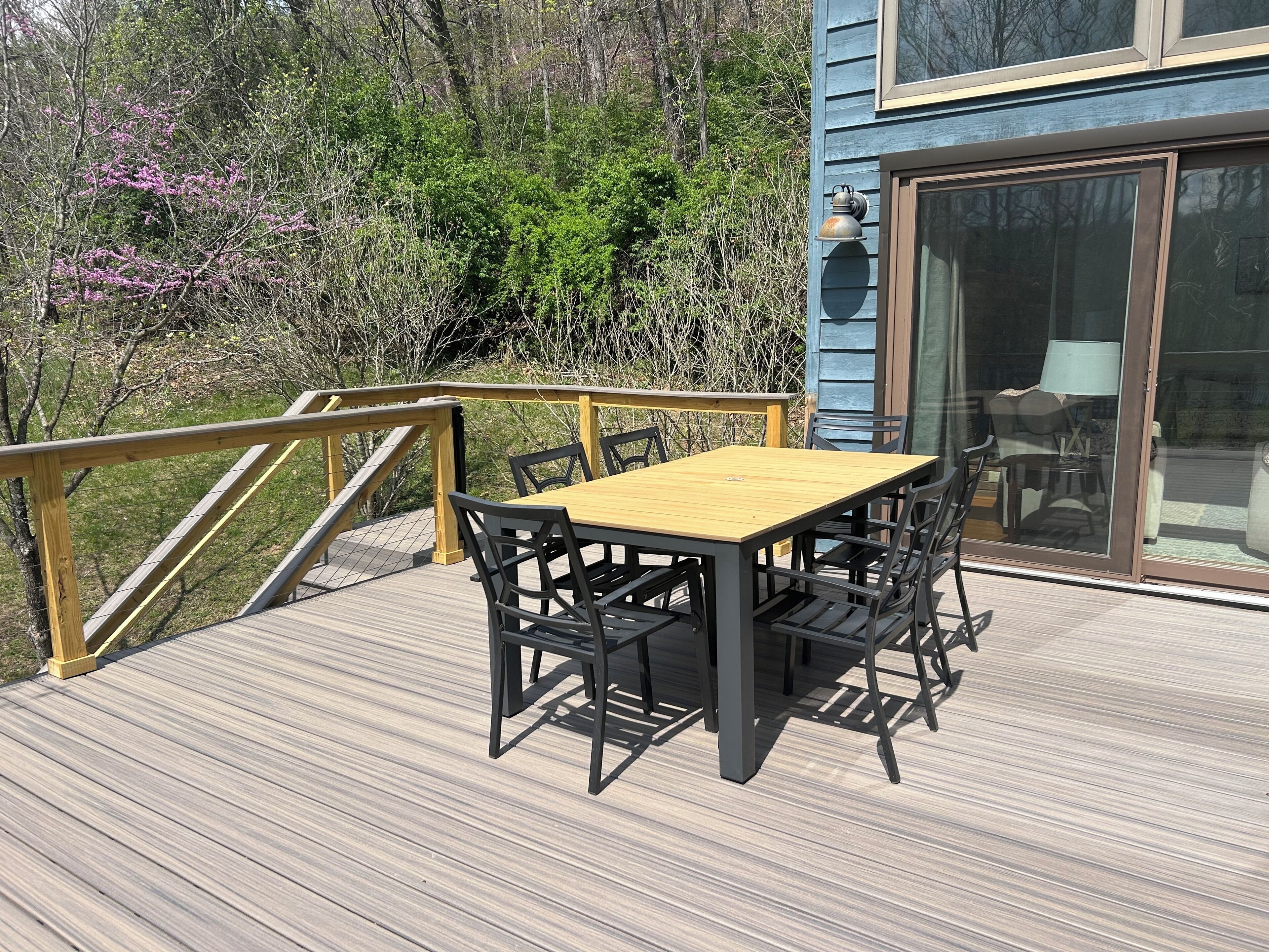 A wooden deck with a table and chairs, a glass door, and a railing.