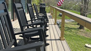 Eine Terrasse mit Sitzgelegenheit und Grill, mit Blick auf eine Wiese mit Bäumen und Bergen.