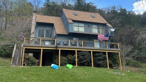 Ein zweistöckiges Haus mit einer Terrasse, einer Flagge und einer Treppe, die zur Terrasse führt.