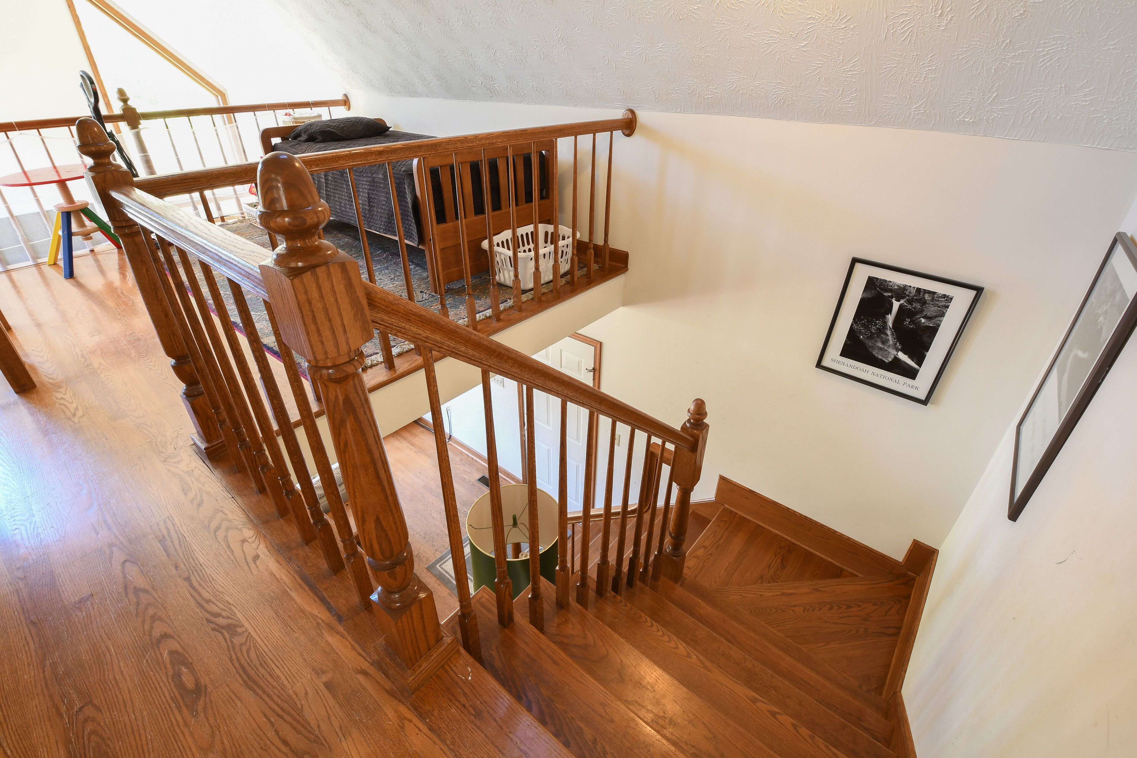 A wooden staircase with a handrail, a white door at the bottom, and a framed picture on the wall.