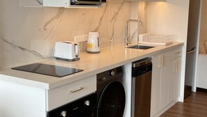 A modern kitchen with a built-in microwave, toaster, kettle, and dishwasher. - Bright & Modern Studio Next to El Olivar Park – San Isidro (San Isidro)