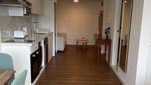 A modern kitchen with white cabinets, a built-in oven, and a dining area with a wooden table and chairs. - Bright & Modern Studio Next to El Olivar Park – San Isidro (San Isidro)