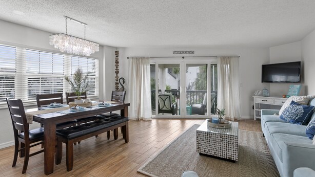 A modern living room with a dining area, a sofa, and a TV.