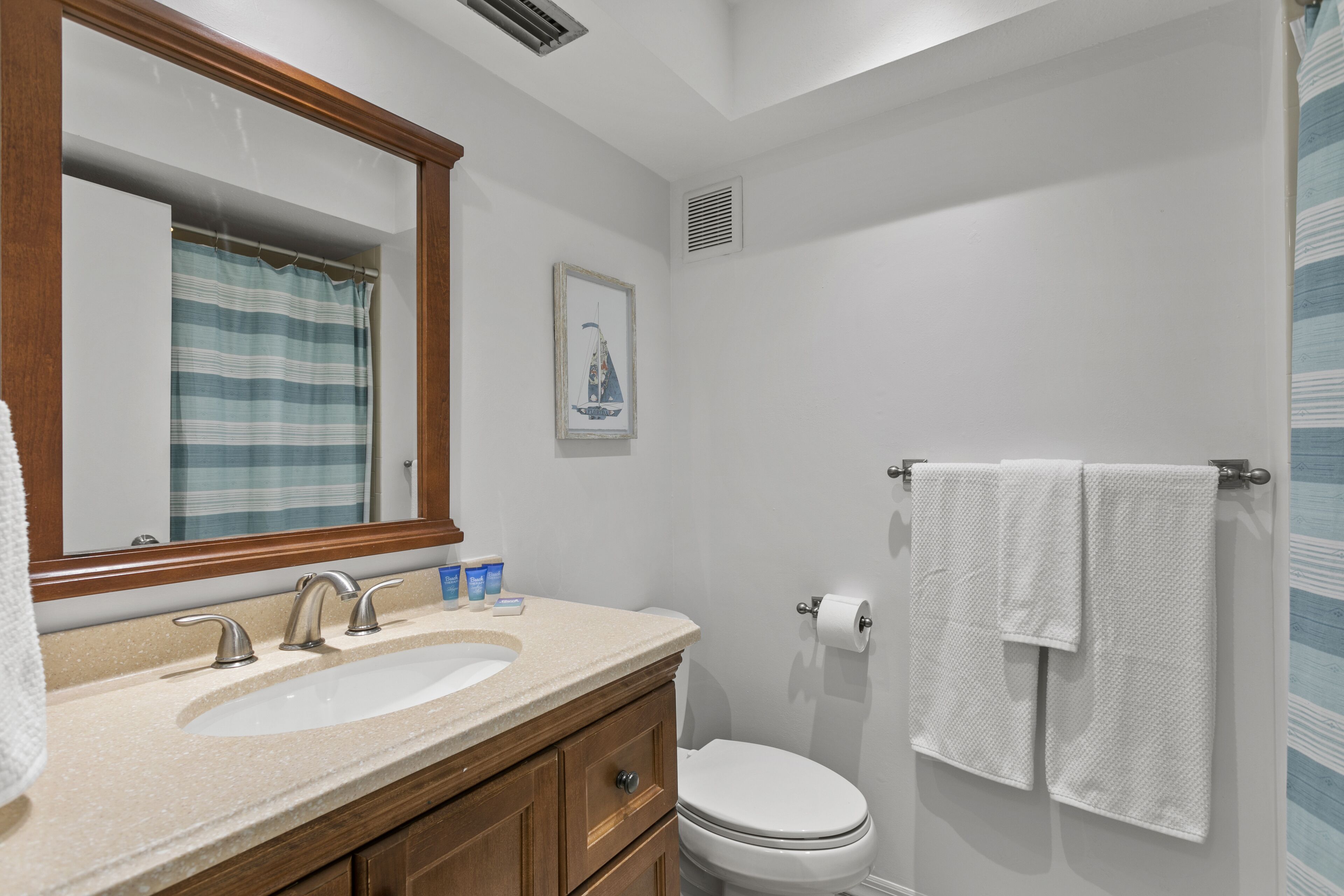 Un bagno con lavandino, specchio, WC e porta asciugamani.