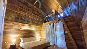 A cozy wooden room with a bed, two bedside lamps, a ceiling fan, and a window with curtains. - Buena Onda - Bungalow Hermosa few steps to the beach (Playa Hermosa)