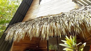 A wooden cabin with a thatched roof, a small porch, and a dining area with a table and chairs. - Buena Onda - Bungalow Hermosa few steps to the beach (Playa Hermosa)