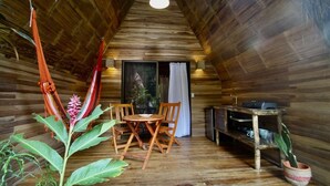 A cozy wooden interior with a dining area, a hanging chair, and a small kitchenette. - Buena Onda - Bungalow Zuma few steps to the beach (Playa Hermosa)