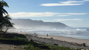 A beach with a clear sky, waves, and a distant mountain. - Buena Onda - Bungalow Zuma few steps to the beach (Playa Hermosa)
