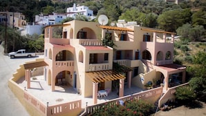A multi-story building with a central courtyard, balconies, and a car parked outside. - Amphitrite Apartments (Kalymnos)