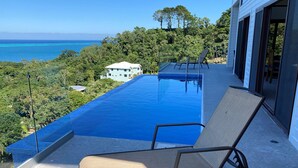 A poolside area with a view of the ocean and a building in the background. - Stunning Turquoise views from this 2 bedroom, 2 bath home... (roatan)