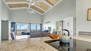 Ein geräumiger Wohnbereich mit einer großen Kücheninsel, Deckenventilator und Blick ins Freie.