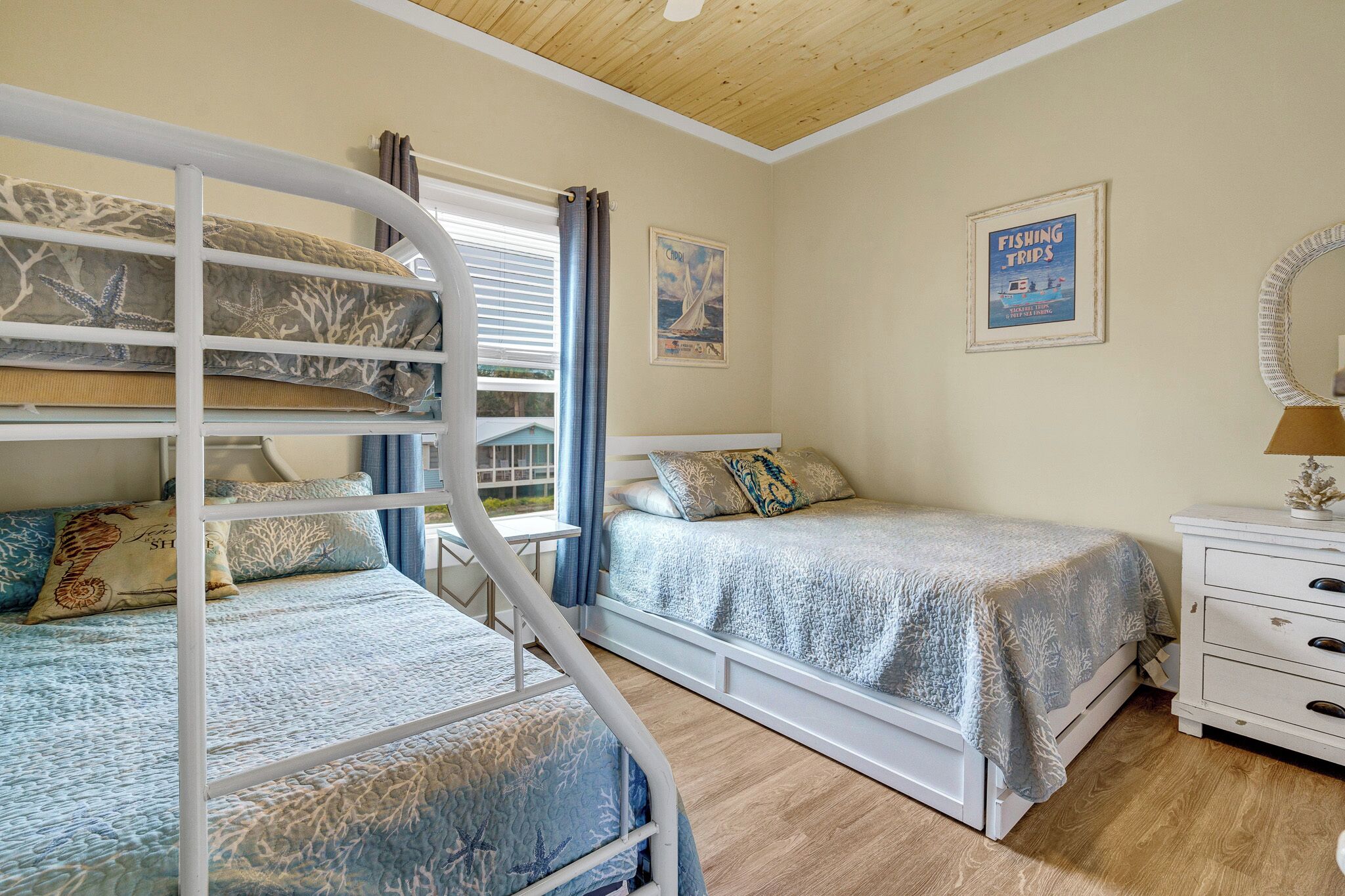 Une chambre avec des lits superposés, un lit simple, une commode et une affiche encadrée au mur.