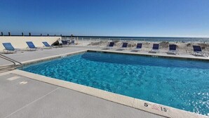 Une piscine à l’eau d’un bleu cristallin, entourée de chaises longues et d’une clôture blanche.
