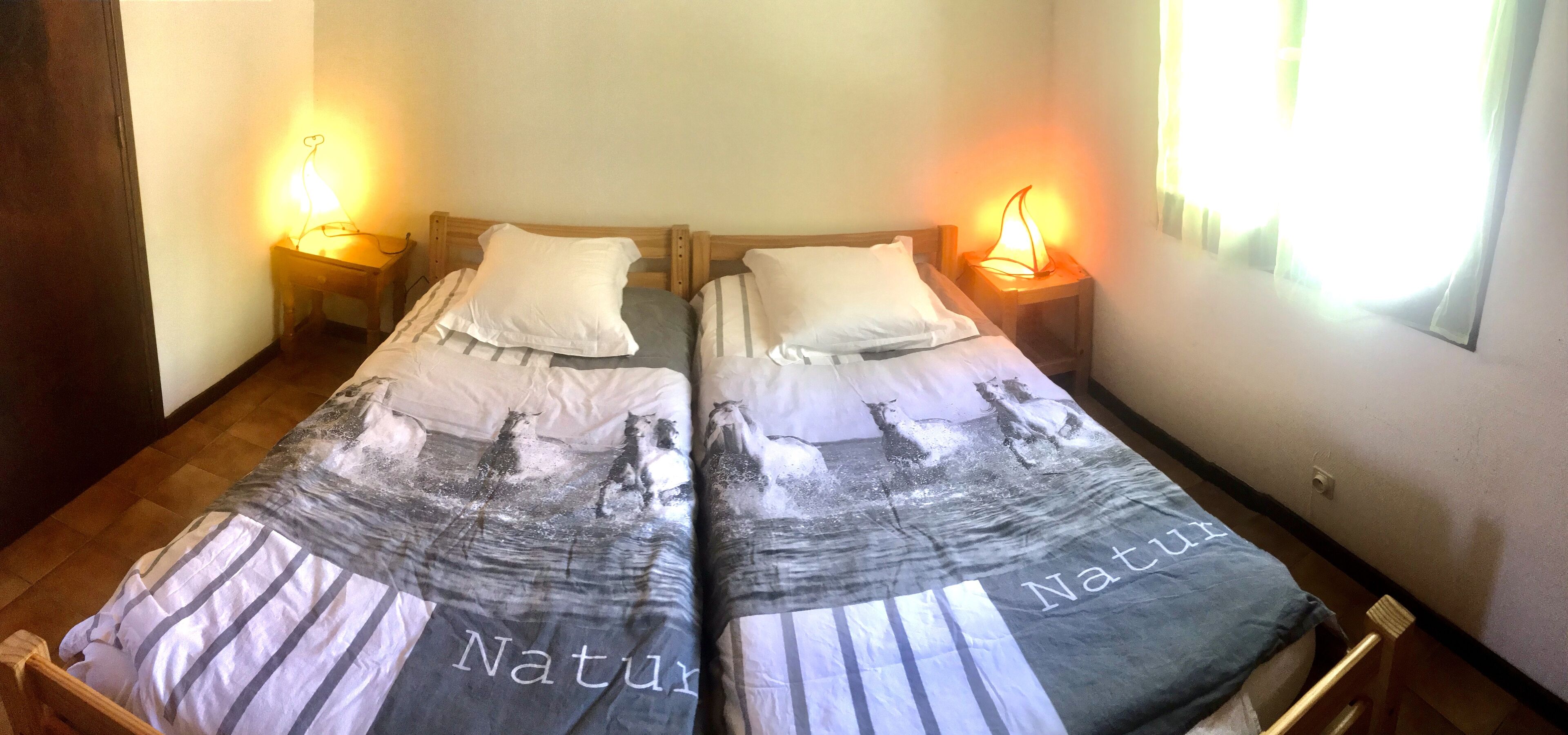 Un lit double avec deux oreillers, une table de chevet et une petite table de nuit avec une lampe.