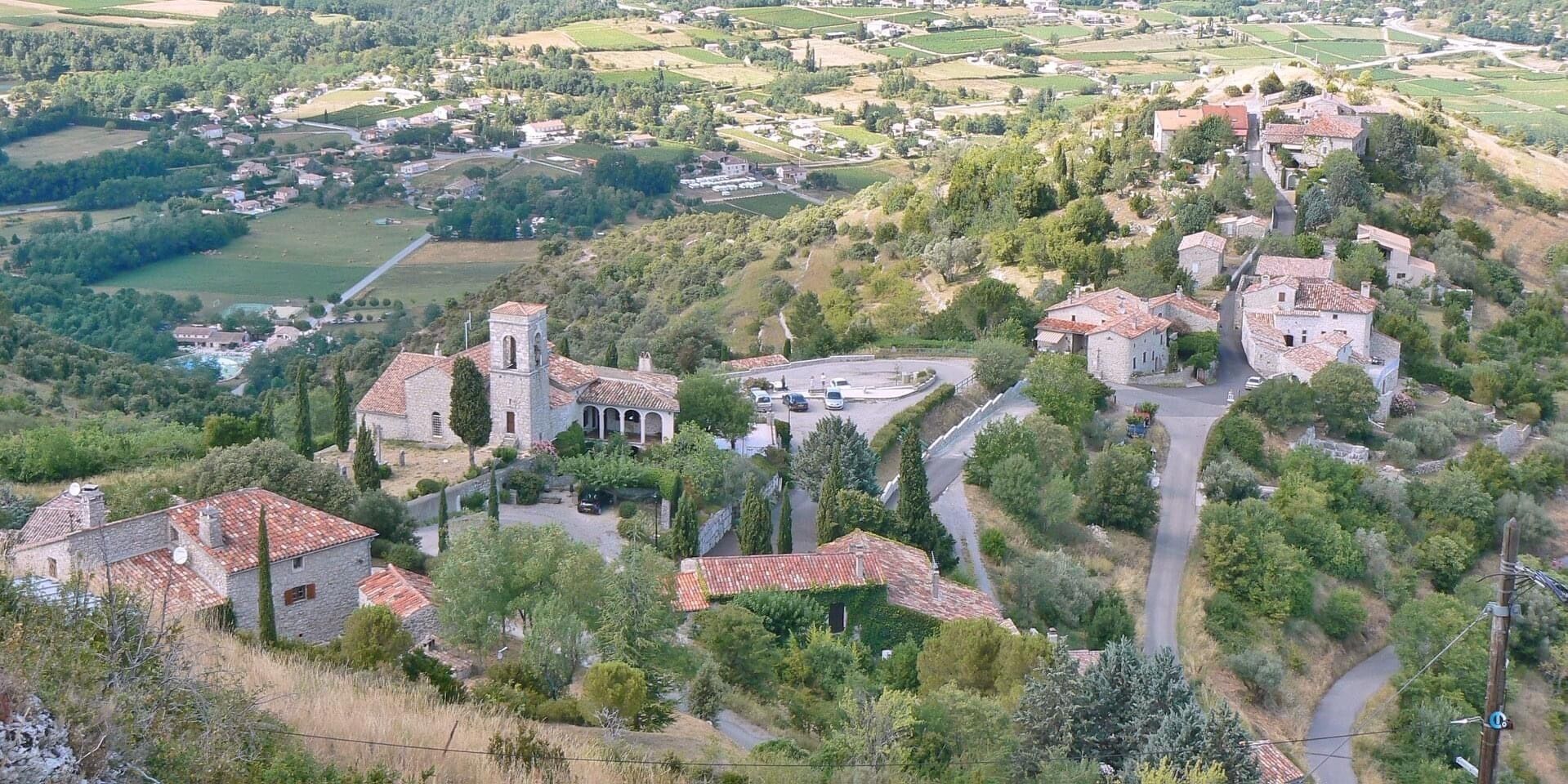 A rural village with stone buildings, a church, and surrounding greenery.