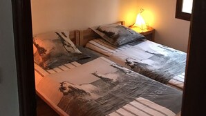 Une chambre à coucher avec deux lits, chacun recouvert d’une couvre-lit à motifs différents. Une lampe de chevet se trouve sur l’un des lits.