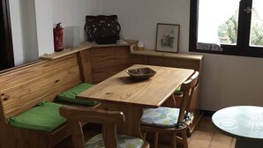 Un coin repas accueillant, avec des meubles en bois, un banc recouvert d’un tissu vert et une petite table sur laquelle se trouve un bol.