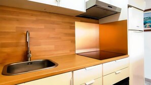 Una cucina moderna con un piano di lavoro in legno, lavello in acciaio inossidabile, mobili bianchi e forno integrato.