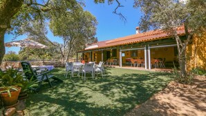 A patio area with outdoor seating, a covered dining area, and a yellow building with a tiled roof. - Casa rural Navalonguilla Santa Olalla del Cala by Ruralidays (Huelva)