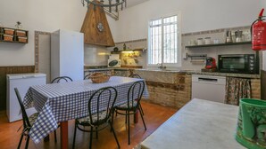 A compact kitchen with a dining area, a clock, a window, and a fire extinguisher. - Casa rural Navalonguilla Santa Olalla del Cala by Ruralidays (Huelva)